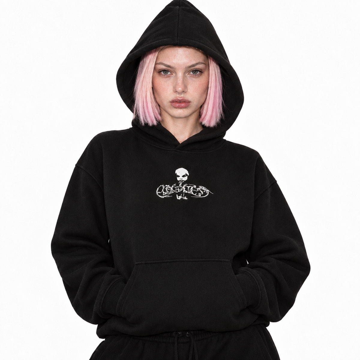 Model in the black fleece hoodie with the white Flawless skull logo, hood up, hands in the pocket.