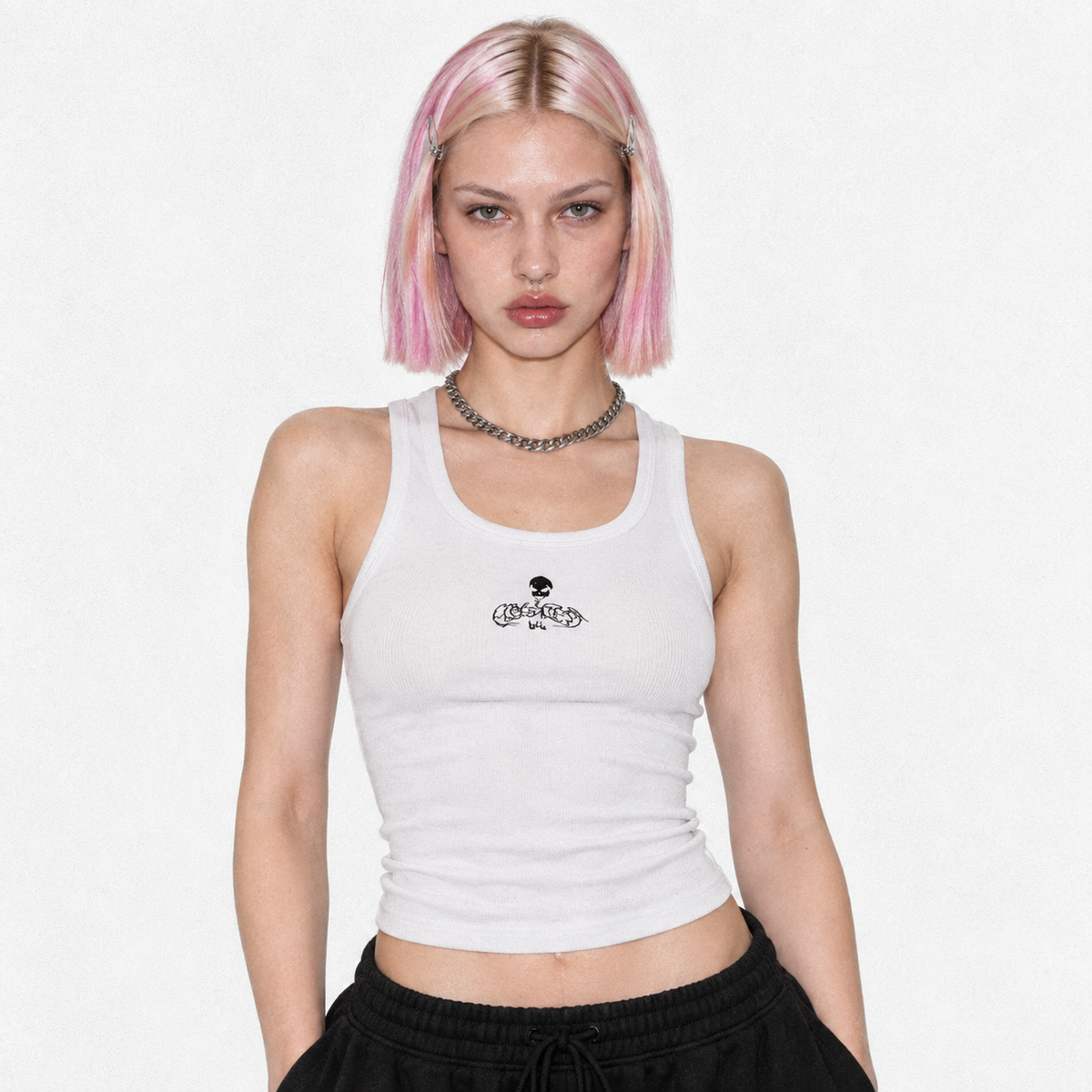 Model in the white ribbed tank top with the small black Flawless skull logo, studio portrait.