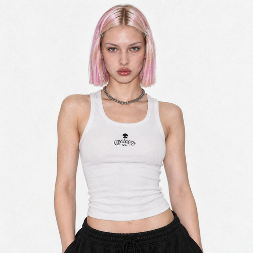 Model in the white ribbed tank top with the small black Flawless skull logo, studio portrait.
